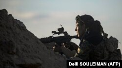 An SDF fighter keeps position at a hilltop as he watches the IS group's last remaining location in the village of Baghouz on March 18.