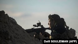Боец «Сирийских демократических сил» на огневой позиции вблизи населенного пункта Багхуз на востоке Сирии. 18 марта 2019 года.