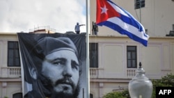 CUBA -- A Cuban flag flutters at half mast near a banner depicting Cuban revolutionary leader Fidel Castro, two days after his death, in Havana on November 27, 2016.