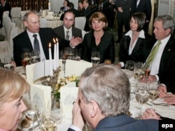Vladimir Putin, la București, în 2008, la masă alături de președintele SUA, George Bush (dreapta), prima doamnă a României, Maria Băsescu (centru), cancelarul Germaniei, Angela Merkel (cu spatele, în stânga jos)