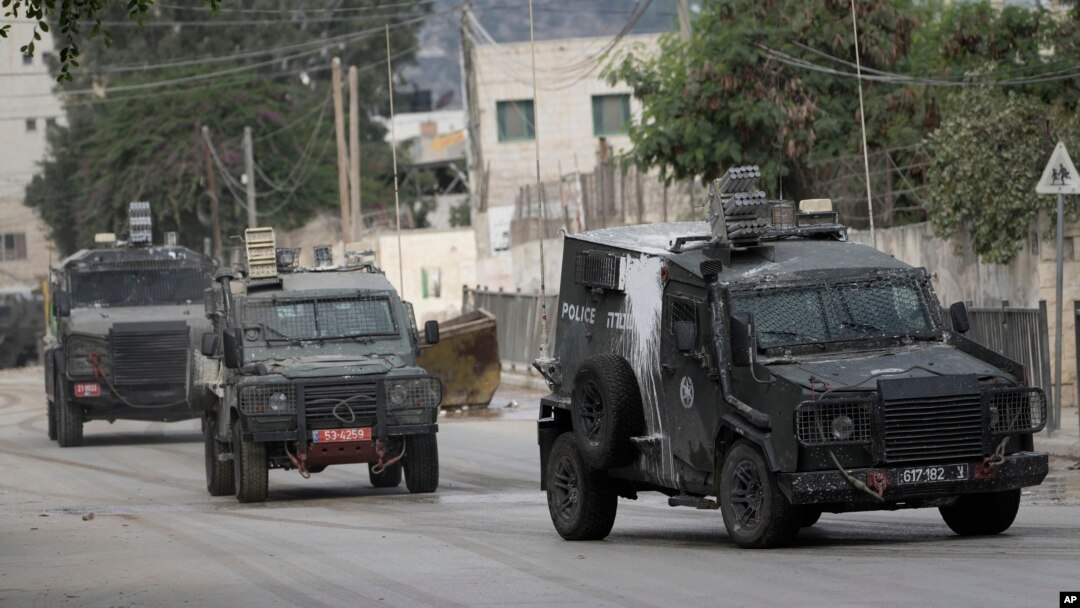 Vehicule blindate israeliene se deplasează pe o stradă în timpul unei operațiuni militare în orașul Jenin din Cisiordania, miercuri, 28 august 2024. 