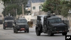 Vehicule blindate israeliene se deplasează pe o stradă în timpul unei operațiuni militare în orașul Jenin din Cisiordania, miercuri, 28 august 2024. 