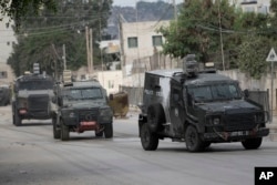 Vehicule blindate israeliene se deplasează pe o stradă în timpul unei operațiuni militare în orașul Jenin din Cisiordania