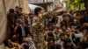 Afghans wait in front of a bank as they try to withdraw money in Kabul on September 12.