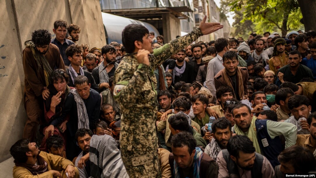 Afghans wait in front of a bank as they try to withdraw money in Kabul on September 12.