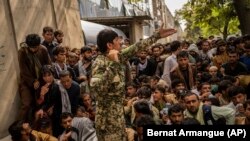 Afghans wait in front of a bank as they try to withdraw money in Kabul.