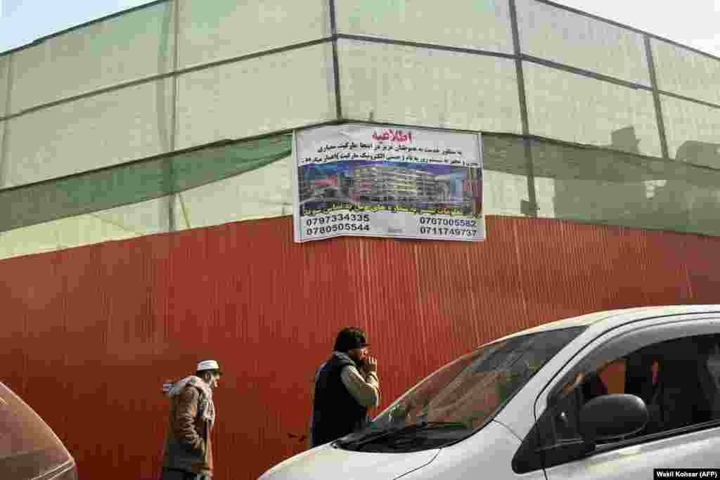Afghans walk by the site of the demolished historical Ariana Cinema in Kabul on December 18. The Taliban government's move to destroy the theater is considered by a number of Afghan cultural figures, filmmakers, and actors to be an attack on the country's cultural heritage.