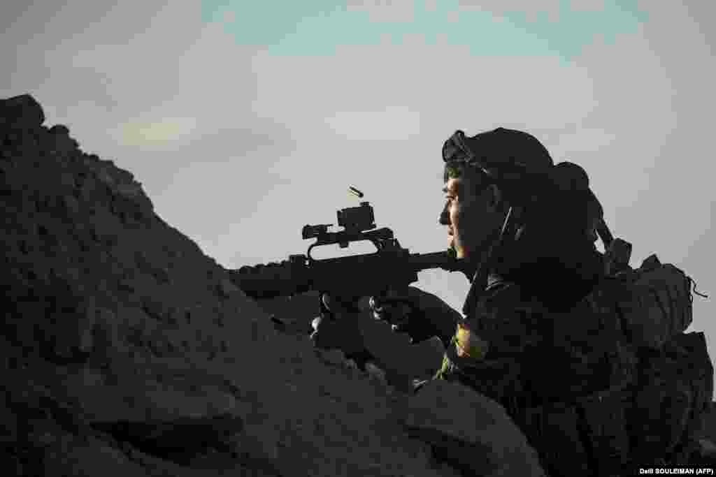 A fighter with the Syrian Democratic Forces keeps position on a hilltop as he watches the Islamic State extremist group&#39;s last remaining location in the village of Baghouz on March 18 during battles with the Kurdish-led SDF in the countryside of the eastern Syrian province of Deir Ezzor.(AFP/Delil Souleiman)