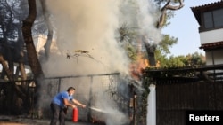 Un bărbat folosește un extinctor pentru a ajuta la combaterea unui incendiu în suburbia Varympompi, la nord de Atena, Grecia, 4 august 2021.