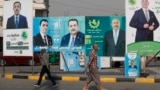 People walk past electoral campaign posters ahead of Iraq's parliamentary elections in central Baghdad on November 6.