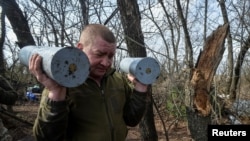 Український військовослужбовець несе снаряди для самохідної гаубиці перед тим, як стріляти в бік російських військ поблизу Бахмута (фото ілюстративне)