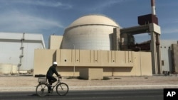 A worker rides a bicycle in front of a reactor building at Iran's Bushehr nuclear power plant. (file photo)