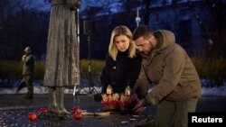 Ukrainian President Volodomyr Zelenskiy and his wife, Olena, visit a monument to Holodomor victims in Kyiv on November 26, 2022. 