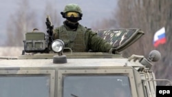 Ukraine -- An armed man in military uniform sits atop of a Russian 'GAZ Tigr' infantry mobility vehicle, outside the territory of a Ukrainian military unit in the village of Perevalnoye, outside Simferopol, 04 March 2014. 