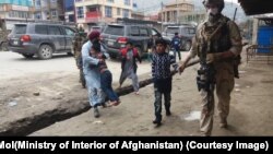 An Afghan soldier walks civilians to safety during an attack on a Sikh temple in Kabul on March 25.