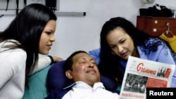 Venezuelan President Hugo Chavez holds a copy of the newspapers with his daughters Rosa Virginia (right) and Maria while recovering from cancer surgery in Havana.