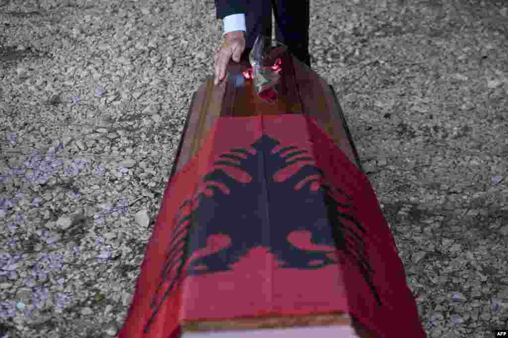 An ethnic Albanian man touches a coffin during a handover ceremony of mortal remains of 12 Kosovar Albanians during a ceremony in the village of Merdare. The remains were found at a mass grave in Serbia, identified 15 years after the war, and will be handed over to the families. (AFP/Armend Nimani)