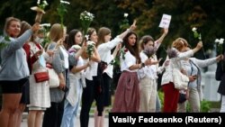 Women hold flowers during a demonstration in Minsk on August 20 against violence following recent protests to reject the presidential election results.
