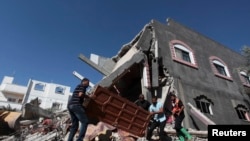 Palestinians carry a door from a destroyed house following what police said was an Israeli air strike in central Gaza on July 9.