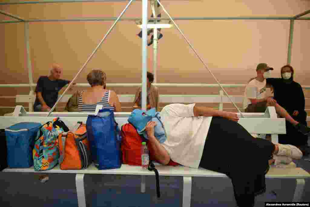 Një grua duke pushuar në një anije, në portin e fshatit Pefki, teksa një zjarr i egër shkrumbonte ishullin e Evias, në Greqi. (8 gusht)