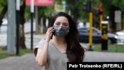 Девушка в защитной маске идет по улице в Алматы. 22 июня 2020 года.