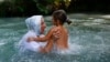 BELARUS -- A woman with a girl dip in cold waters of Golubaya Krinitsa, (Blue Spring) during celebration of Orthodox Honey Savior, which is also called the Savior on Water, near the town of Slavharad, August 14, 2019