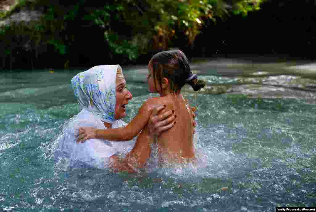 A woman and a girl take a dip in the cold water of the Golubaya Krinitsa (Blue Spring) during celebrations of Orthodox Honey Savior, which is also called the Savior on Water, near the town of Slavgorod, Belarus. (Reuters/Vasily Fedosenko)