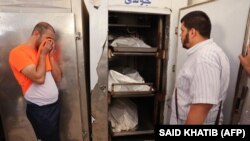 تصویر آرشیف: دو مرد فلسطینی در کنار اجساد سه تن از افرادی که در خشونت های فلسطین و اسرائیل کشته شده اند.