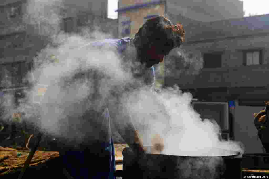 A vendor boils water chestnuts in a drum to sell at a workplace in Karachi, Pakistan. (AFP/Asif Hassan)