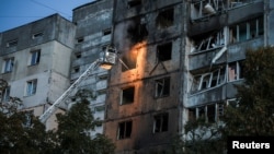 Ukrainian firefighters work at a site of an apartment building hit during a Russian drone strike on Kyiv on September 3. 