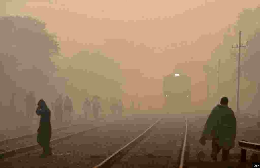 People walk alongside a railway track on a foggy day in Lahore, Pakistan. (AFP/Arif Ali)