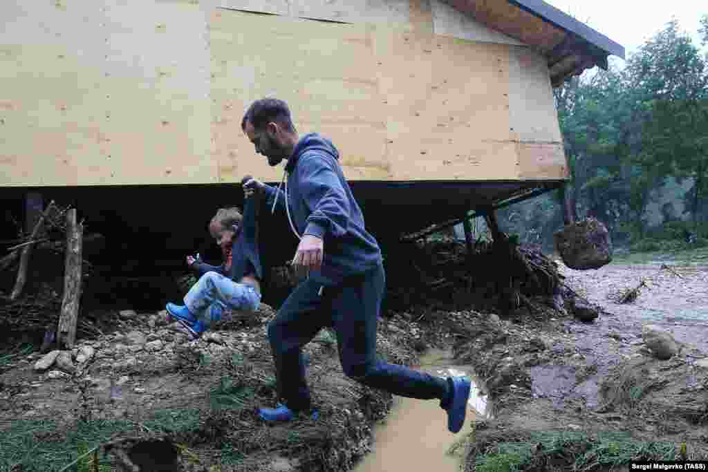 Местные жители рядом с домом, поврежденным наводнением в селе Аромат в Крыму