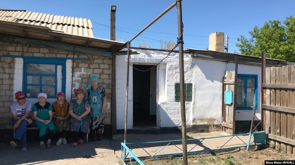 Ğalı Baqtıbaevtıñ tuıstarı belsendi atıp öltirilgen üydiñ aldında otır. Qarağandı oblısı, Atasu auılı, 1 mausım 2019 jıl.