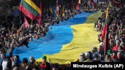 Lithuanians carry a giant Ukrainian flag to protest against the Russian invasion of Ukraine, in Vilnius in March 2022.