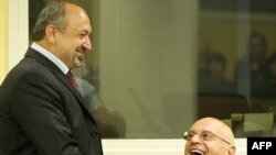 Bosnian Serb army officers Vujadin Popovic and Ljubisa Beara chat in the courtroom before their sentencing.