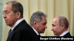 Глава МИД России Сергей Лавров (на переднем плане), президент России Владимир Путин (справа) и министр обороны Сергей Шойгу