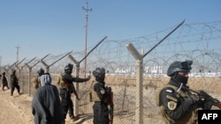 Iraqi forces stand guard outside Camp Ashraf, home to exiled Iranian opposition members, during a December 9 protest by Iraqis calling for the camp to be closed.