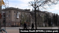 Місцеві жителі йдуть повз пошкоджені російськими обстрілами будинки у центрі Дружківки, Донецька область, квітень 2026 року
