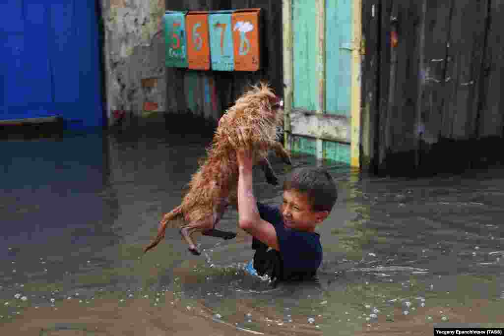 A boy carries a dog on a flooded street in the Siberian city of Chita in Russia&#39;s Transbaikal region. (TASS/Evgeny Epanchintsev)