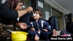 Izbeglička porodica iz Iraka - baka i unuk sede na podu Železničke stanice u Sarajevu