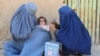 Afghan health workers administer a polio vaccine to a child in Kandahar.