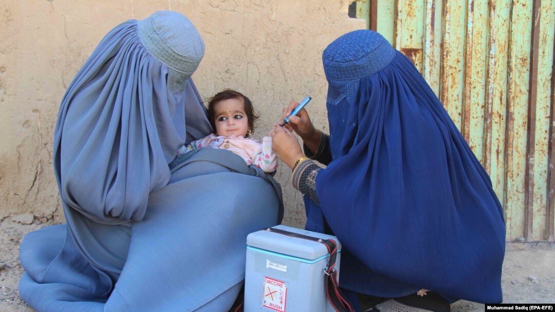 Afghan health workers administer a polio vaccine to a child in Kandahar.