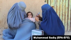 Afghan health workers administer a polio vaccine to a child in Kandahar.