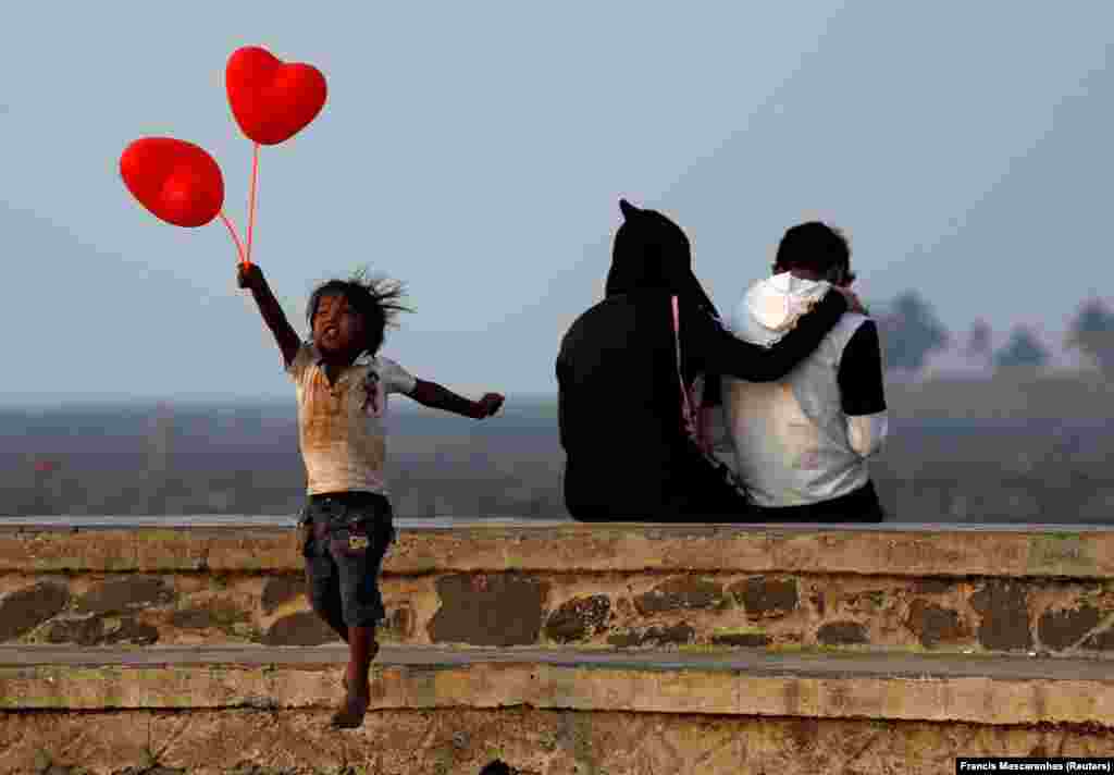 A child jumps from a promenade after attempting to sell heart-shaped balloons to a couple on Valentine&#39;s Day in Mumbai. (Reuters/Francis Mascarenhas)