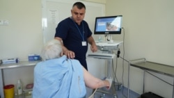Medicul oncolog Nicolae Dolganiuc efectuează dermatoscopia unei paciente.