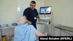 Medicul oncolog Nicolae Dolganiuc efectuează dermatoscopia unei paciente.