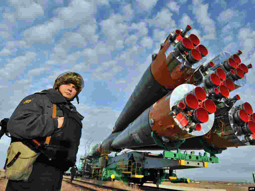 A Russian policeman stands guard near a Soyuz TMA-18 spacecraft as it is delivered to its Baikonur launchpad in March 2010.