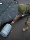 A Ukrainian officer points to a thermobaric charge from a downed Shahed drone launched by Russia from an undisclosed location in Ukraine.