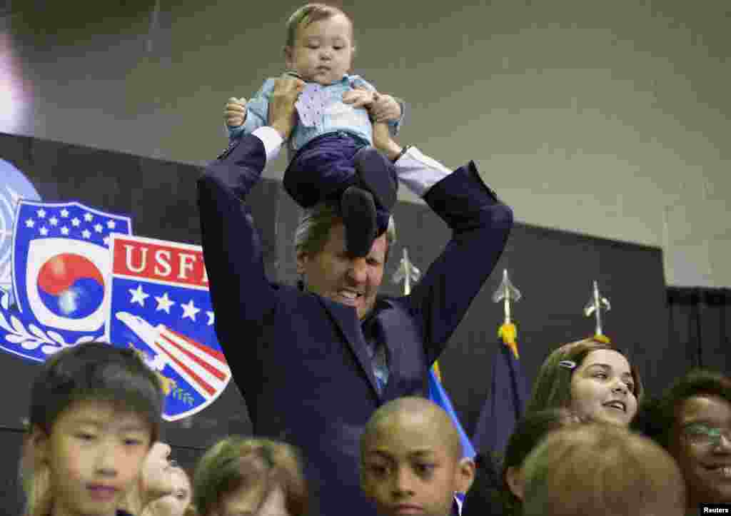 U.S. Secretary of State John Kerry puts 8-month-old Andrew Belz on his shoulders as he poses for photos with the children of U.S. troops and U.S. Embassy personnel at Collier Field House at Yongsan Garrison in Seoul. (Reuters/Saul Loeb)