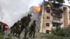 Georgian soldiers run past a building hit by a Russian air strike in Gori on August 9, 2008. 
